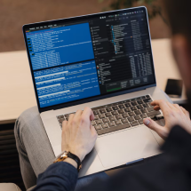 Hands typing on a laptop showing code