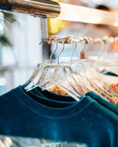 Teal shirts on hangers on a clothing store rail