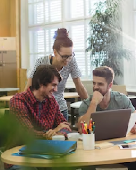 Three colleagues working around a laptop at a round table